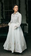 Load image into Gallery viewer, Photo of woman standing outdoors wearing prairie dress.  Model is truning and skirt is full.  Hands are in the pockets of the apron.
