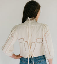 Load image into Gallery viewer, Back view of brunette woman standing in front of a white studio backdrop, wearing 205 Gibson Girl Blouse with hand left hand on her hip.

