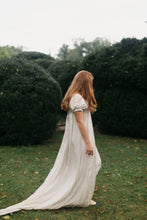 Load image into Gallery viewer, Side view of red head young woman standing surrounded greenery wearing 215 Empire Dress.
