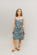 Load image into Gallery viewer, Woman wearing a teal, white, and black floral knee-length dress with narrow straps.
