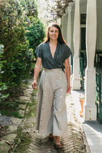 Load image into Gallery viewer, Young brunette white woman walking surrounded by greenery wearing the 231 Big Sky Riding skirt buttoned giving the effect of pants.
