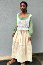 Load image into Gallery viewer, Black woman wearing a cream quilted skirt with a green blouse and white crocheted camisole on top - in front of a grey wall.
