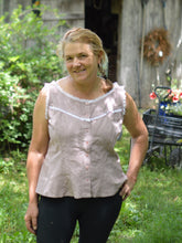Load image into Gallery viewer, smiling middle aged white blonde woman standing with left hand on her hip wearing sleeveless camisole in pale pink with white ruffle lace and black athletic leggings with greenery in the background
