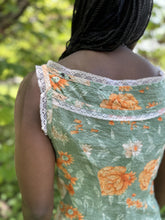 Load image into Gallery viewer, close up of back of sleeveless camisole in floral green and orange, worn by an african american woman with braided hair.
