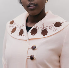 Load image into Gallery viewer, Black woman wearing a pink wool coat with brown leaf applique and embroidery on cuffs and collar.
