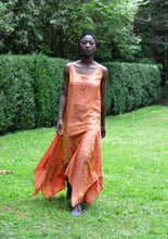 Load image into Gallery viewer, Young African woman standing surrounded by greenery wearing #264 Monte Carlo Dress in orange.
