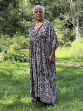 Load image into Gallery viewer, Woman standing outside wearing a long pink and black printed kaftan.
