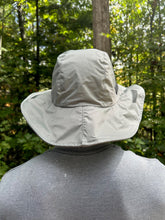 Load image into Gallery viewer, Person wearing a light-colored norwester hat in a forest setting
