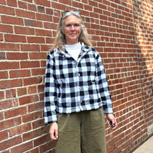 Load image into Gallery viewer, Woman standing in front of a brick wall wearing a black and white buffalo plaid polar lodge jacket.
