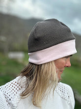 Load image into Gallery viewer, Head shot of woman standing outside wearing a grey and pink border beanie.  Side view
