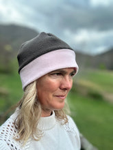 Load image into Gallery viewer, Head shot of woman standing outside wearing a grey and pink border beanie.

