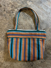 Load image into Gallery viewer, Striped fabric bag with colorful pattern on a concrete surface
