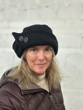 Load image into Gallery viewer, Woman wearing a black roll brim hat with two buttons on it.
