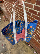 Load image into Gallery viewer, blue floral tote with red pocket and white straps, photo from above shows the black hang strap
