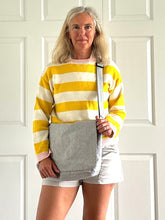Load image into Gallery viewer, Woman wearing a yellow and white striped sweater with a gray courier bag against a white background
