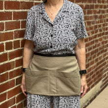Load image into Gallery viewer, Person wearing a floral shirt and beige tool belt apron against a brick wall.
