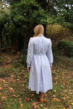 Load image into Gallery viewer, Back of the Calico Day Dress in blue on a woman standing in a lawn
