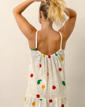 Load image into Gallery viewer, Woman wearing a white dress with colorful floral patterns on a plain background
