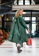 Load image into Gallery viewer, Back view of a blonde white woman looking over her shoulder holding a woven purse wearing 254 Swing Coat open.
