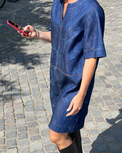 Load image into Gallery viewer, Person wearing a blue denim dress on a cobblestone street.
