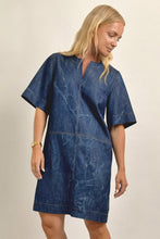 Load image into Gallery viewer, Woman wearing a blue denim dress against a beige background
