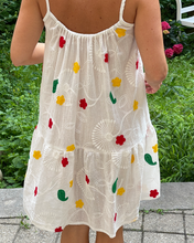 Load image into Gallery viewer, White dress with colorful floral patterns worn by a person outdoors.
