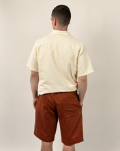Load image into Gallery viewer, Man wearing a beige shirt and rust-colored shorts against a plain background
