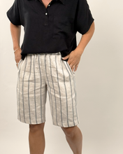 Load image into Gallery viewer, Person wearing a black shirt and striped shorts on a plain background
