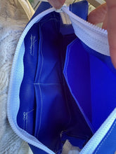 Load image into Gallery viewer, Close-up of the inside of a blue bag with white trim being held open.
